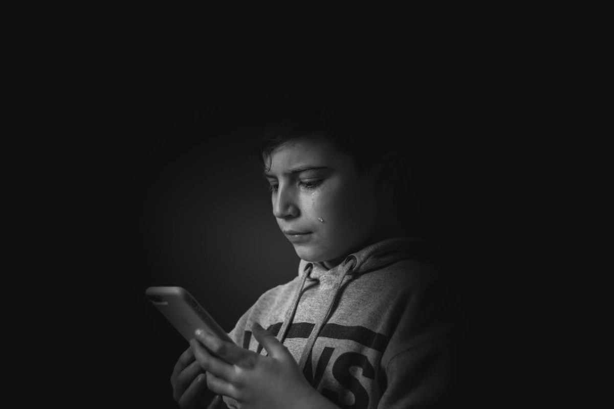 Sad kid using a smartphone